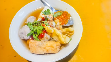 Thai noodle soup with fish ball in white plate on table