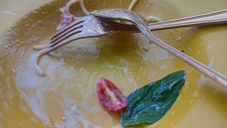 Close up of spaghetti carbonara with basil leaf and tomato on top