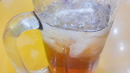 Ice tea in a glass on a yellow background. Close-up.