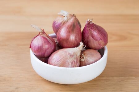 shallots in bowl on old wooden tableの写真素材