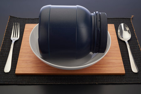 Black jar on plate with spoon and knifeの写真素材