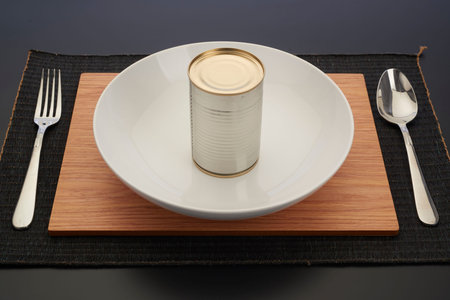 Tin can put on plate with spoon and knife