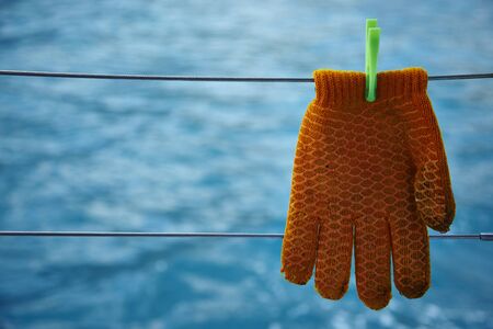 gloves drying in the open air hanging on sea backgroundの写真素材