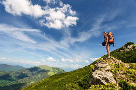 Young woman with backpack standing on cliffの写真素材