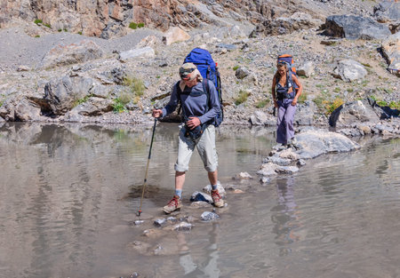 Two hikers crossing mountain river. Fany mountain. Tadjikistanの写真素材