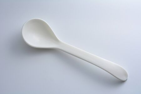 White spoon on gray background with shadowの写真素材