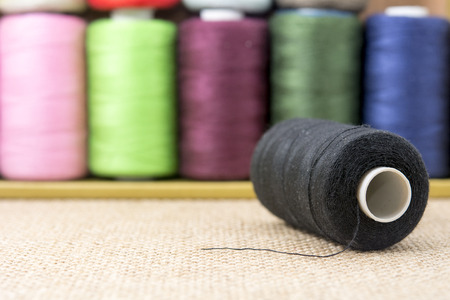 Black spools of thread on sackcloth tableの写真素材