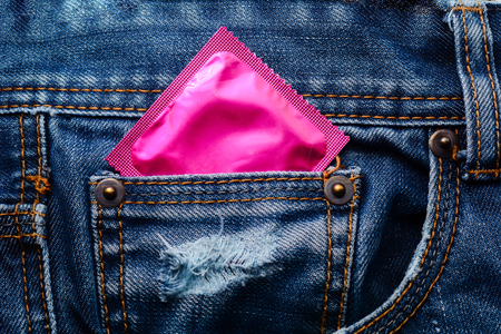 Pink condom in the pocket of a blue jeansの写真素材