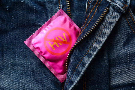 Pink condom on jeans zipper -Stop hiv or aids conceptの写真素材