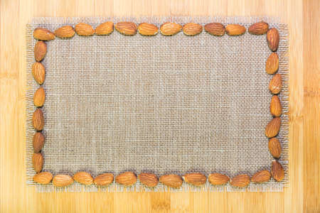 Almond around sackcloth on wooden table with copy spaceの写真素材