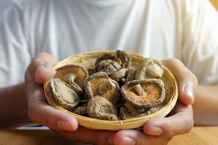 Dried Chinese mushroom in basket on hand - closeupの写真素材