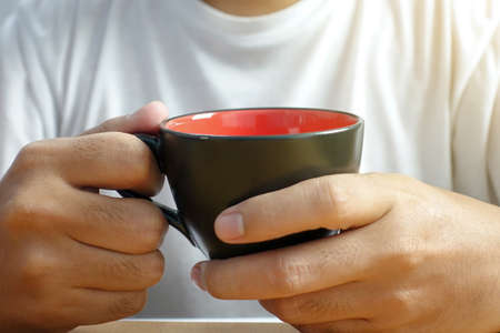 man hands holding hot cup of coffee or tea - closeupの写真素材