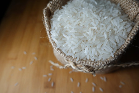 rice in burlap sack on wooden table - closeup