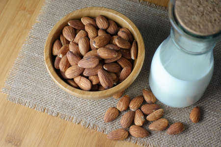 Almond milk with almonds on table and bowlの写真素材