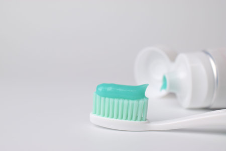 Green toothpaste on a toothbrush on white background - closeup