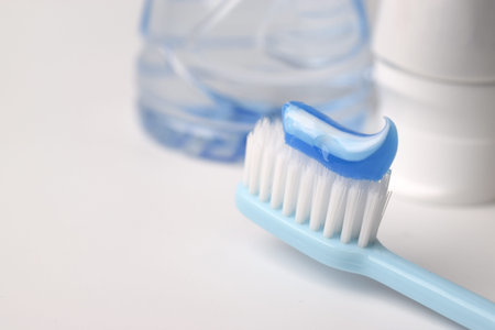 Blue toothpaste on a toothbrush on white background - closeup