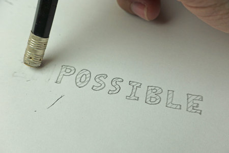Changing the word impossible to possible with a pencil eraser, closeup