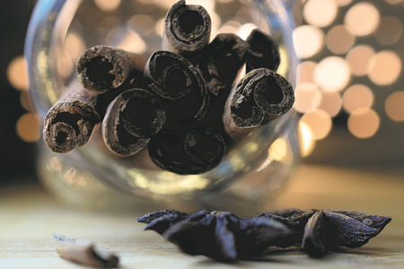cinnamon sticks in glass jar on wooden with blurred lights, closeupの写真素材