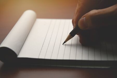 Male hand with pencil writing on notebook. Male working in home officeの写真素材