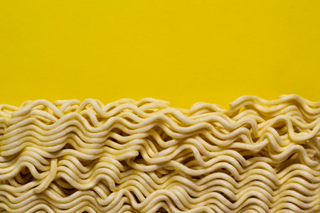 Uncooked instant noodles isolated on yellow backgroundの写真素材
