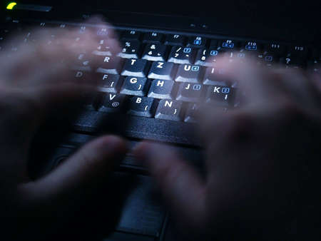 Late night work on laptop. Alight keyboard with typing handsの写真素材