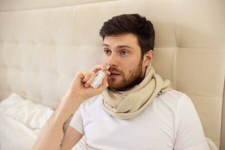 Sick Man Using Nasal Spray. Ill Man at Home Using Nose Sprayの写真素材