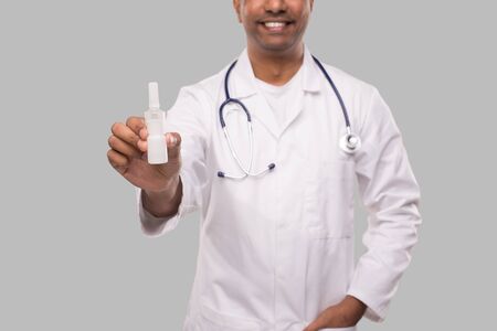 Doctor Holding Nose Spray Close Up Isolated. Indian Man Doctor with Nasal Spray in Hands. Medicineの写真素材