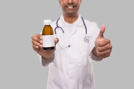 Indian Man Doctor Holding Cough Syrup Showing Thumb Up Close Up Isolated. Medicの写真素材