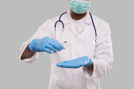 Doctor Using Hands Sanitizer Wearing Medical Mask and Gloves Close Up. Indian Man Doctor Holding Hands Wash Antiseptic. Corona Virus Concept. Isolated Medicの写真素材