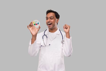 Doctor Excited Examing Petri Dish Isolated. Indian Man Doctor Medicine, Science Conceptの写真素材