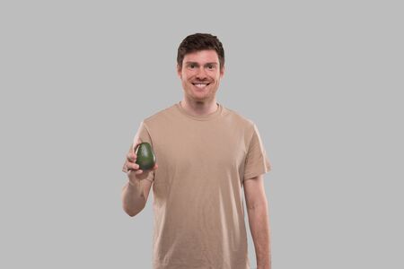 Man Smilling Holding Avocado Isolated. Healthy Food Conceptの写真素材
