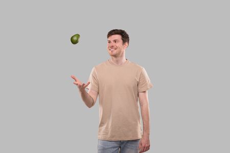 Man Smilling Throwing Avocado Up Isolated. Man Catching Avocado. Healthy Food Conceptの写真素材