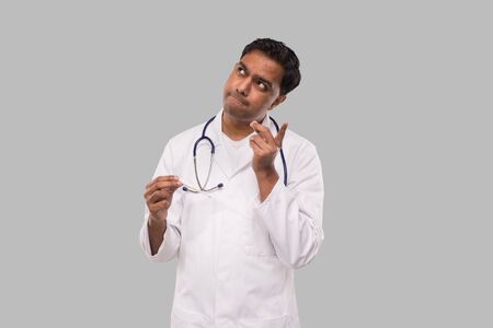 Doctor Watching Thermometer Thinking Isolated. Indian Man Doctor Analysing with Thermometer in Hands. Healthy Life, Doctor, Virus Conceptの写真素材