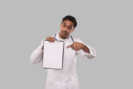 Doctor Pointing at Clipboard Isolated. Indian Man Doctor Blank Clipboard in Handsの写真素材