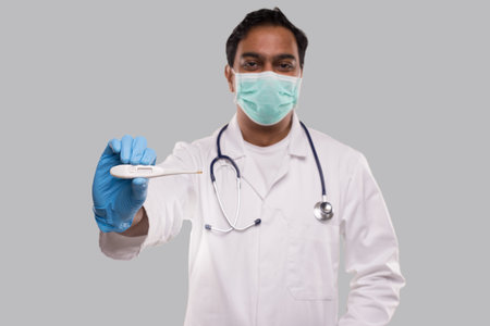 Doctor Showing Thermometer Wearing Medical Mask and Gloves Isolated. Indian Man Doctor with...