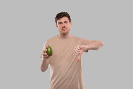 Man Showing Avocado and Thumb Down Isolated. No Avocado, Stop Avocado Conceptの写真素材