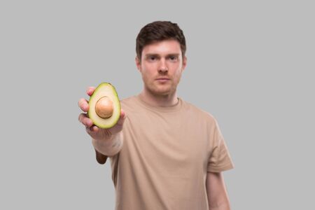 Man Showing Avocado Serious Face Isolated. Avocado Cut in Half. Healthy Food, No Avocado, Stop Avocado Conceptの写真素材
