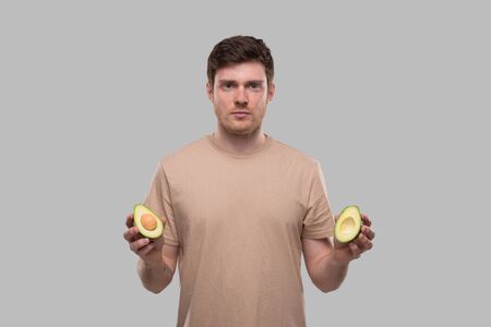 Man Holding Cut in Half Avocado Isolated. Man Serious Face. No Avocado, Stop Avocado Conceptの写真素材
