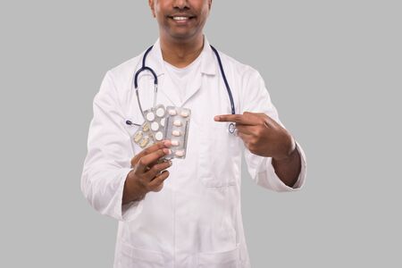 Man Doctor Pointing at Pills Close Up. Doctor Holding Tablets. Indian Man Doctor Isolated.の写真素材