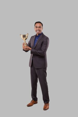 Businessman Holding Trophy. Indian Businessman Standing Full Length with Trophy in Handsの写真素材
