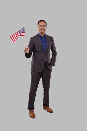 Businessman Waving American Flag. Indian Businessman Standing Full Length with USA Flag in Handsの写真素材