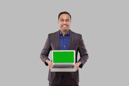 Businessman Showing Laptop Green Screen Isolated. Indian Business man with Laptop in Hands. Online Business Conceptの写真素材