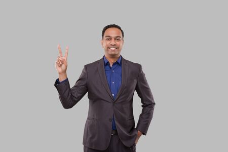 Businessman Showing Peace Sign Isolated. Indian Business man Standing Smillingの写真素材