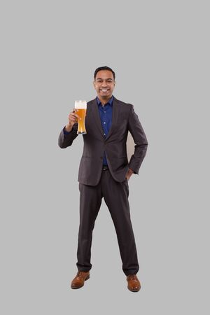 Businessman Holding Beer Glass. Indian Business man Standing Full Length with Beer in Handの写真素材