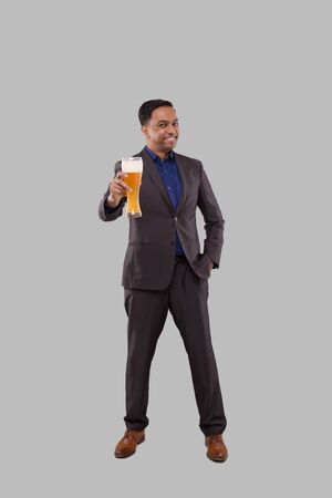 Businessman Showing Beer Glass. Indian Business man Standing Full Length with Beer in Handの写真素材