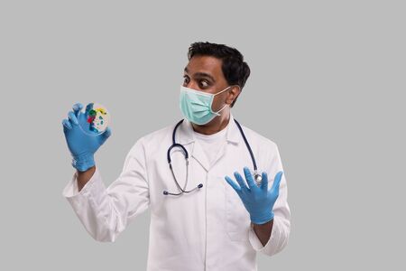 Indian Man Doctor Surprised of Petri Dish Wearing Medical Mask and Gloves Isolated. Medicine, Science Conceptの写真素材