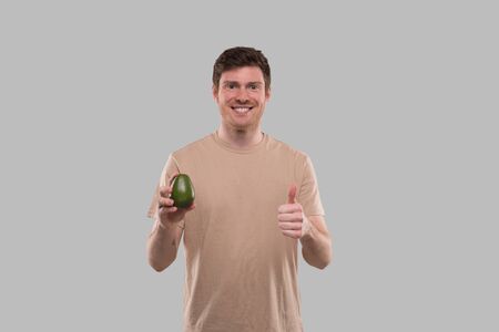 Man Holding Avocado and Thumb Up Isolated. Healthy Life, Eat Green Conceptの写真素材