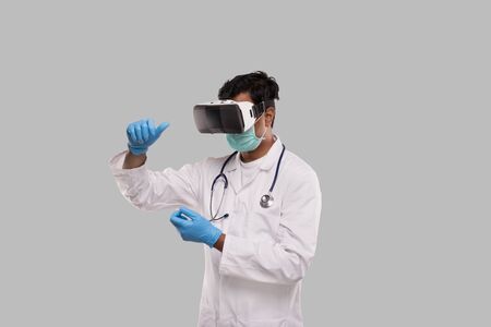 Doctor Wearing VR Glasses, Medical Mask and Gloves Hands in Front Isolated. Indian Man Doctor Holding in Virtual Realityの写真素材
