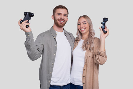Couple Standing with Joysticks in Hands Smilling Isolated. Happy Couple Playing Console Games.の写真素材