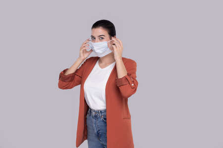 Girl Puts on Medical Mask Isolated. Woman In Shirt with Medical Mask. Health, Virus, Medical Conceptの写真素材